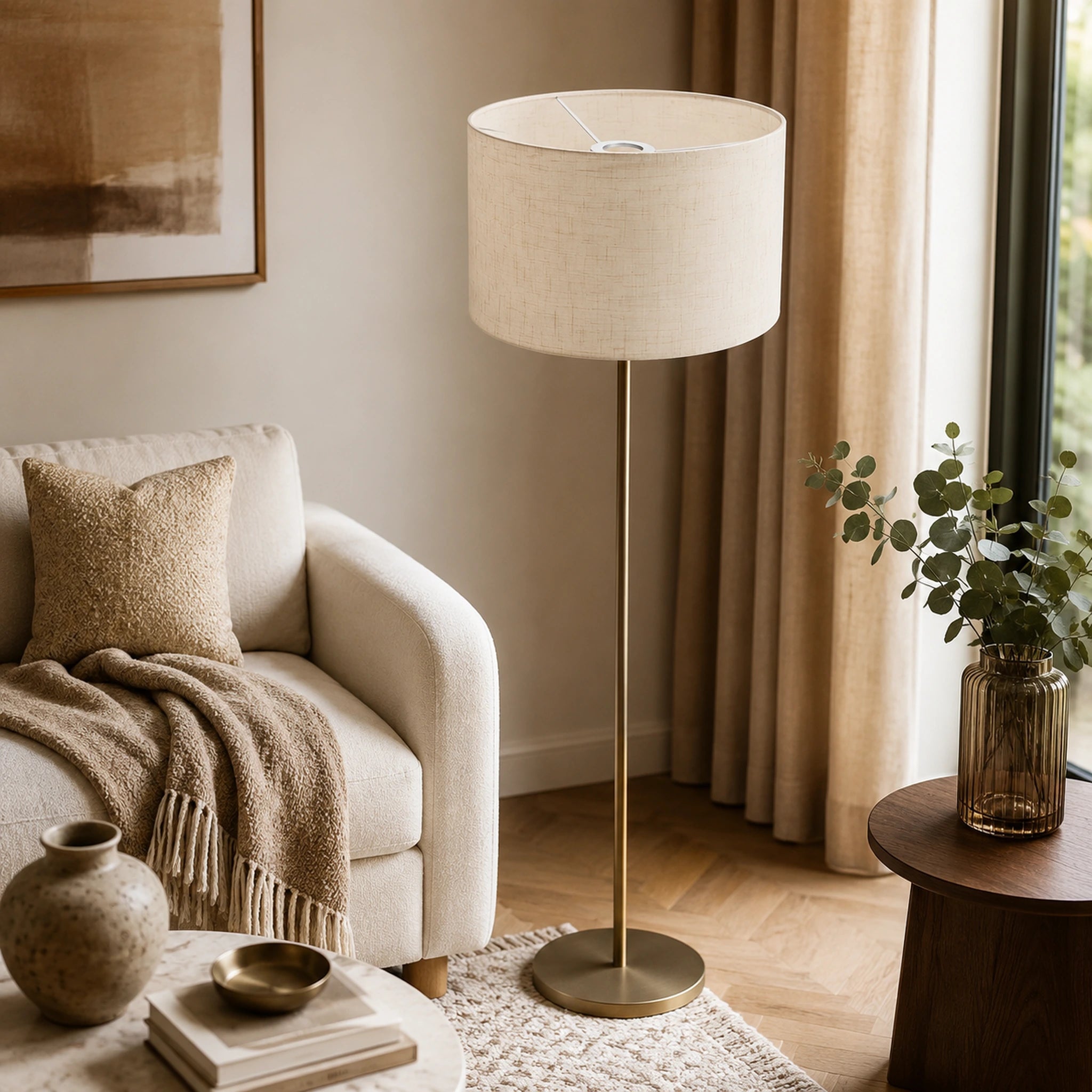 Abat-jour en lin naturel monté sur un lampadaire à pied laiton doré dans un salon chaleureux aux tons beiges Image