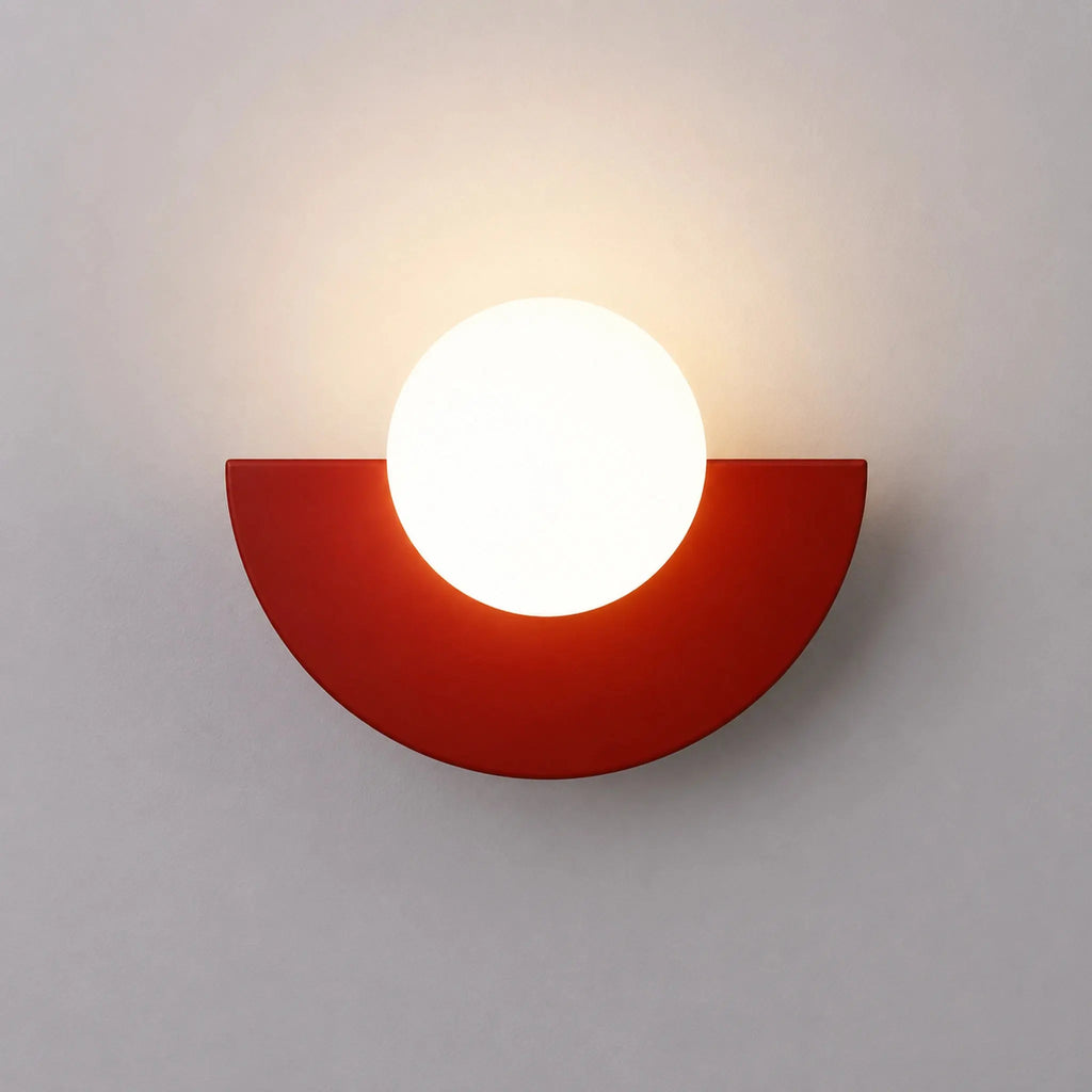 Abat-jour mural rouge en demi-lune avec boule en verre dépoli allumée, vue de face sur fond neutre