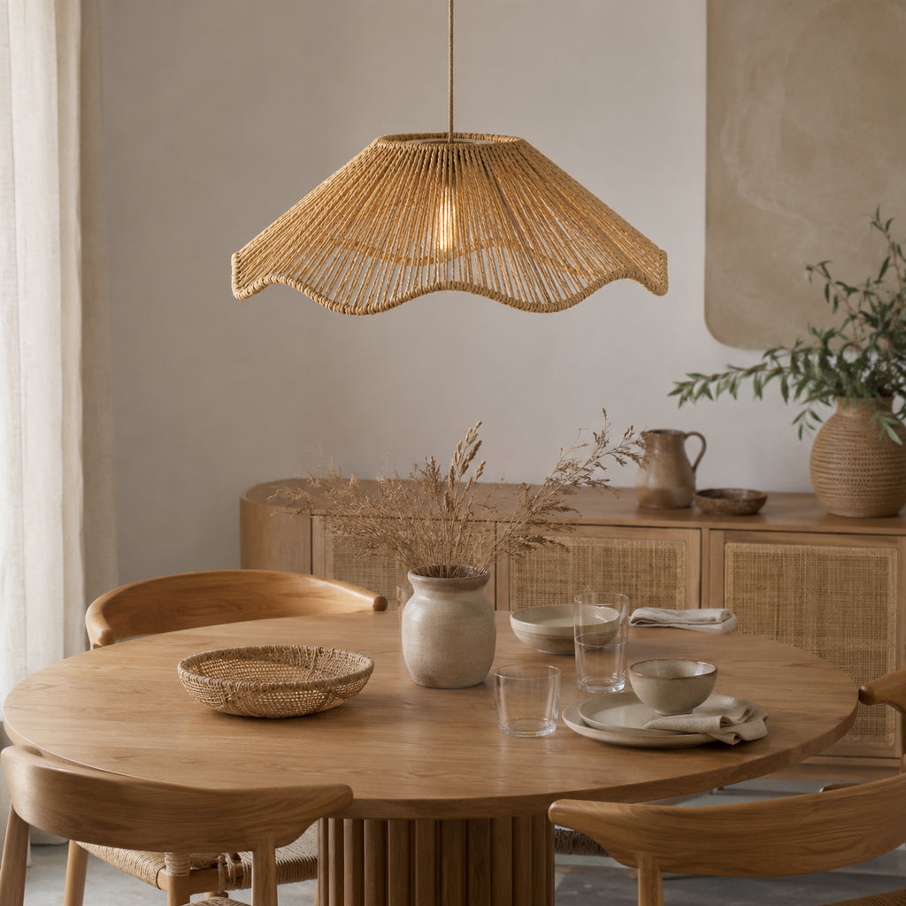 Suspension en rotin naturel tressé au-dessus d’une table à manger en bois dans un intérieur chaleureux