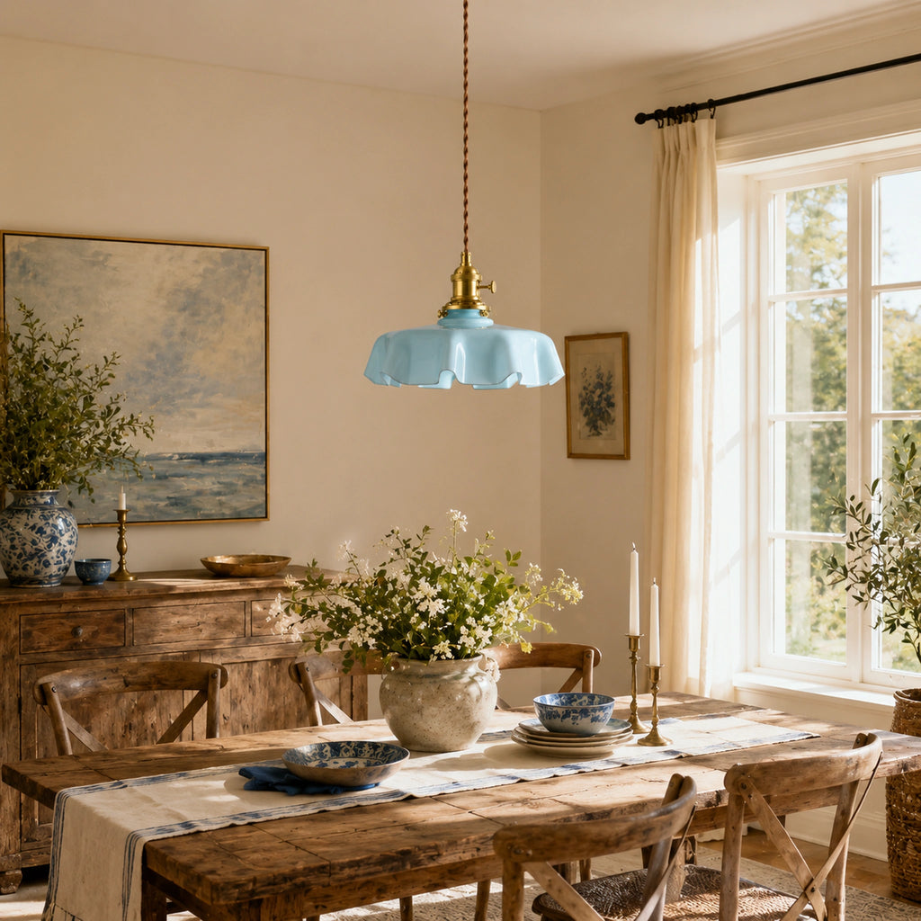 Abat-jour en verre opalin bleu pastel forme fleur suspendu au-dessus d'une table rustique en bois dans une salle à manger lumineuse