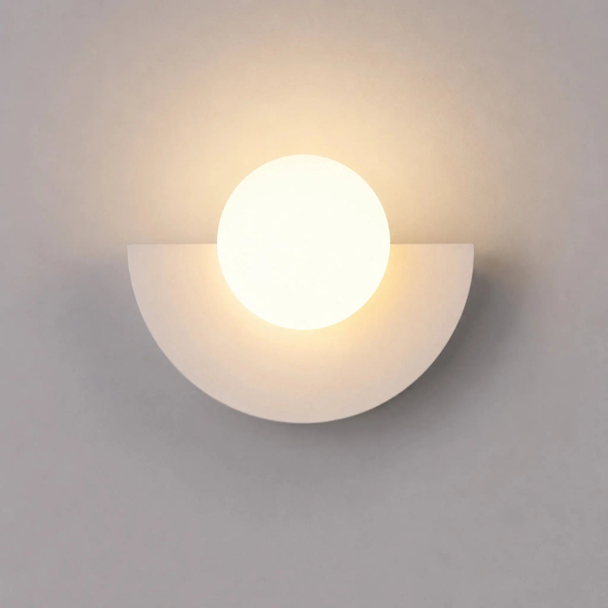 Abat-jour mural blanc en demi-lune avec boule en verre dépoli, vue de face sur fond neutre